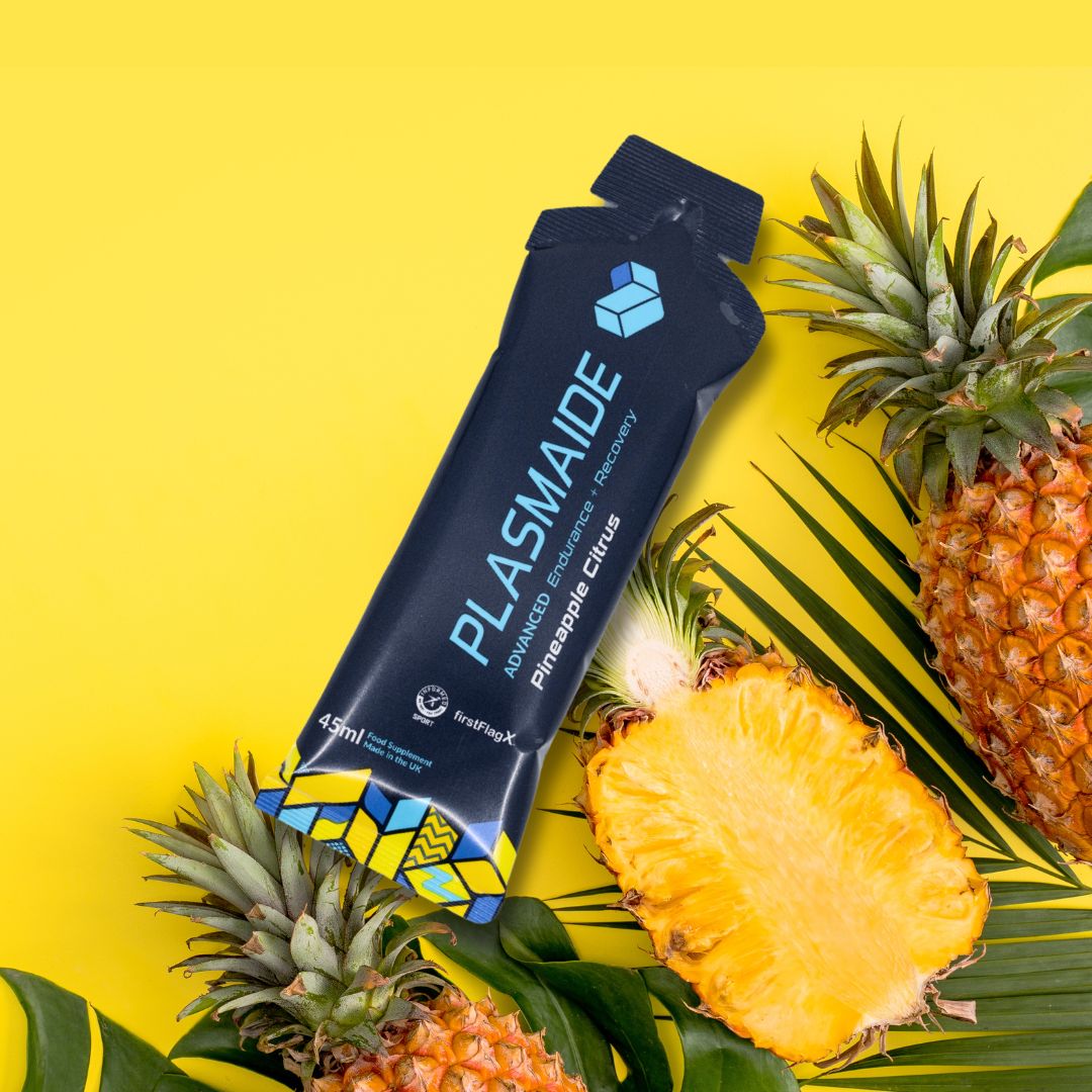 Single-serve Plasmaide Pineapple Citrus beverage in a clear glass, showcasing vibrant yellow-orange liquid with pineapple and citrus slices.