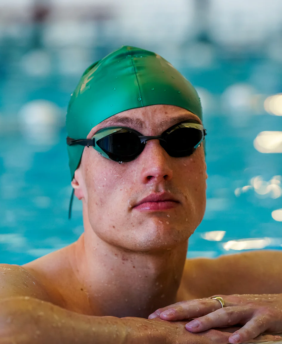 Orange silicone swim cap by HUUB, designed to fit snugly and reduce water drag during swimming.